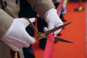 Close-up Of Businesspeople Hand Cutting Red Ribbon With Scissors. Red ribbon cutting for open new project.