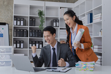 Two employees working at table in a modern office, Asian man and a woman work at office desk, Business campaign result and project planning concept, financial planning,  