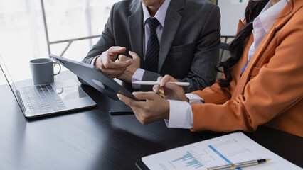 Two employees working at table in a modern office, Asian man and a woman work at office desk,...