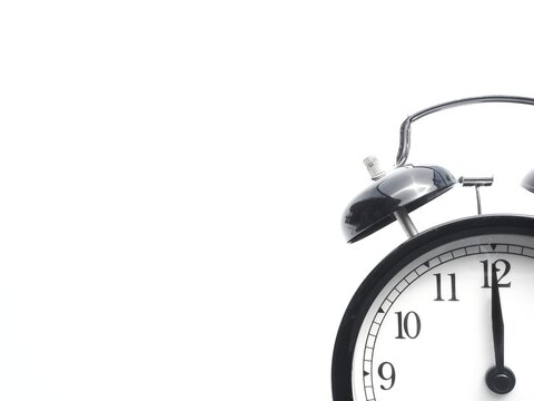 Black retro alarm clock at 12 o clock on a white background with copy space to add text