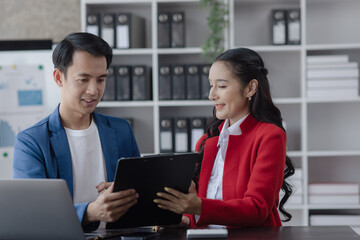 Two employees working at table in a modern office, Asian man and a woman work at office desk, Business campaign result and project planning concept.  