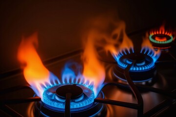 Orange and blue flame gas nozzles on a stove on a dark background