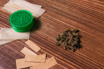 Top view of cannabis flowers with accessories around them on a wooden table.