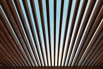 Wooden sunshade roof structure is under blue sky on a sunny day