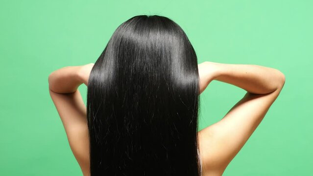 Close Up Back View Of A Woman Using Her Hands Flipping Her Long Black And Blond Straight Healthy Hair In The Green Screen Background Studio
