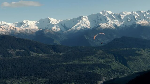 Person flying on paraplane above beautiful peaks of the Caucasus Mountains. It is located in the Svaneti region of Georgia.
