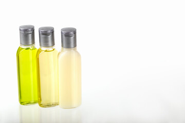 Three small bottles of cosmetics on white background with copy space. Shampoo, shower gel, body lotion. Travel, trips, hotels. Cosmetics mockup, advertising