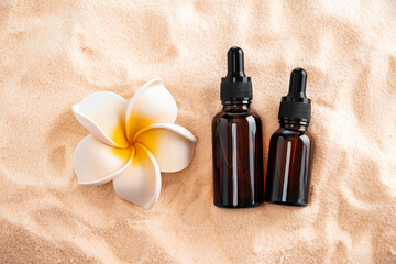 Top view essential oils and plumeria flower on a sandy beach. - Powered by Adobe