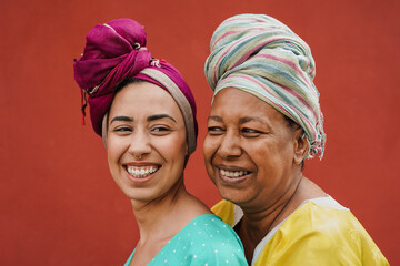 African mother hugging adult daughter while wearing traditional dress and turban
