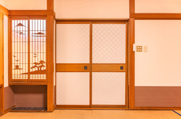 Wall of a typical traditional Japanese room featuring tatami mats covering the floor, fusuma doors and shoji window made of rice paper with wooden decorations evocating a landscape of the mount Fuji.
