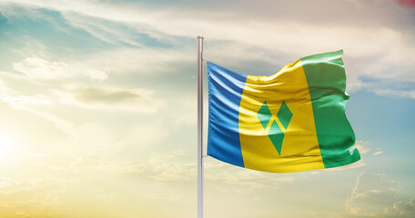 Saint Vincent and the Grenadines national flag waving in beautiful sky. The symbol of the state on wavy silk fabric.