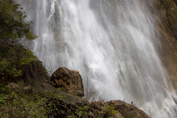 Zona inferior y humeda de la cascada de El Salt de Alcoy con hierbas y roca en primer plano. España
