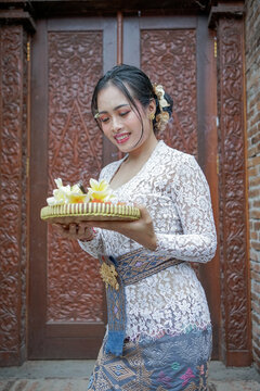 A beautiful Balinese woman with the traditional costume carrying the canang flower