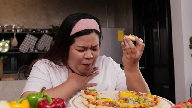 Asian fat woman eating pizza She ate in a hurry, had a choking on her throat. Fast food concept. lose weight
