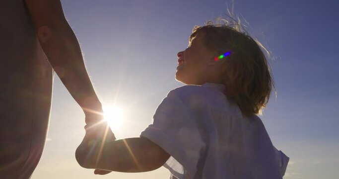 Niece walks with her aunt holding hands. Happy and satisfied niece, illuminated by rays of sun, walks with her aunt outside in nature and holds her hand. Strong family ties. Girl and woman are walking