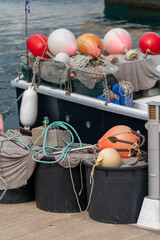 Buoys, anchor, nets, and other fishing tackle on the pier and fishing boat.