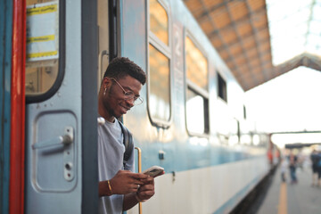 portrait of young man on a train while using a smartphone