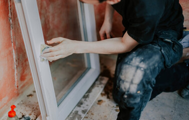 Caucasian male is washing window frame with sponge.