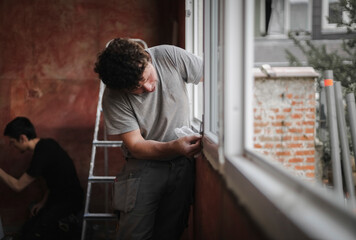 Caucasian man cleans the window frame.