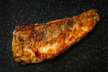 Fried hake fish on a black background, grilled fish in batter