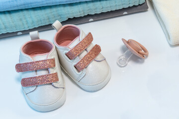 Baby girl pink shoes with other newborn baby accessories on white surface. Baby concept