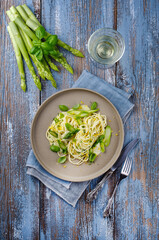 Traditionelle italienische Spaghetti mit Spargel in Kräuter Sauce serviert als Draufsicht auf einem Nordic Design Teller