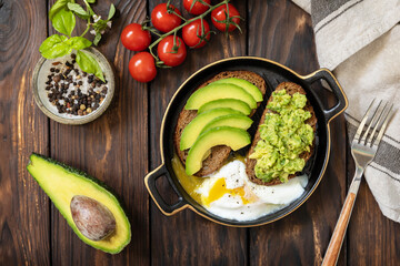 Healthy breakfast, sandwich with avocado and egg. Wholemeal bread toast sliced avocado and poached egg on a rustic table. View from above.