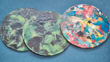 Colorful three trivets or coasters made of multicolored recycled plastic lids