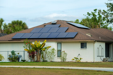 Aerial view of regular american home roof with blue solar photovoltaic panels for producing clean...