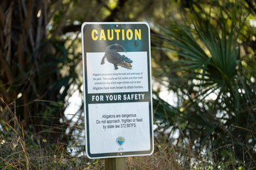 Alligators warning sign in Florida state park about caution and safety during trail walk