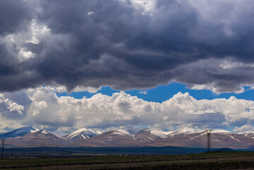 Obraz premium Panoramic landscape with snowy mountains and dramatic clouds