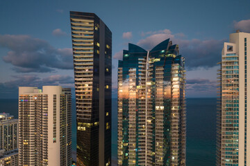 Night urban landscape of downtown district in Sunny Isles Beach city in Florida, USA. Skyline with brightly illuminated high skyscraper buildings in modern american megapolis