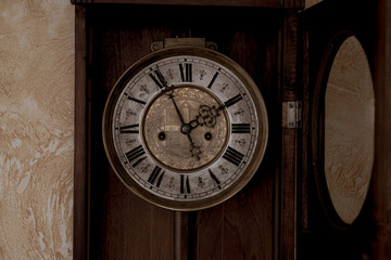 Old wooden clock with a pendulum hanging on the wall	