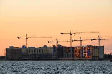 Obraz premium Tower lifting cranes at high residential apartment buildings construction site. Real estate development