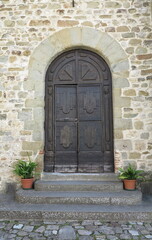 Fototapeta na wymiar Umbertide San Francesco Church Wooden Entrance with Steps and Plants in Umbria, Italy
