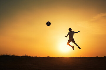 Fototapeta na wymiar atleta de futebol de silhueta chutando bola no ar