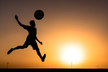 Naklejka premium atleta de futebol de silhueta chutando bola no ar