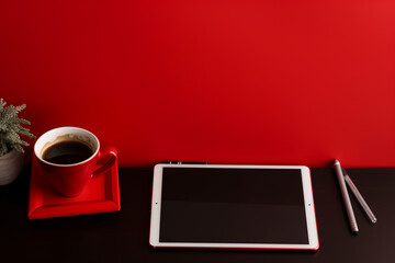 Local de trabalho com computador tablet, notebook e copo perto da parede vermelha - obrazy, fototapety, plakaty