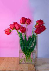 Bouquet of red tulips in a glass vase on a wooden table