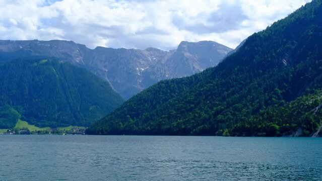 picturesque evening lake Achensee in Austria, green mountains rises above the calm expanse of water, concept of the beauty of nature, vacation by the reservoir, water sports, resort place tyrol
