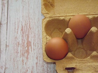 beige chicken eggs in an egg box on a light wooden background