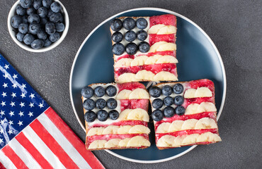 Obraz premium American flag sandwiches with blueberry, banana and berry jam on toast bread on blue plate, View from above