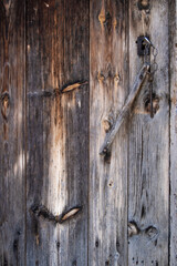 an old wooden door, weathered by the passage of time with an antique key inserted in the lock, worn wooden texture