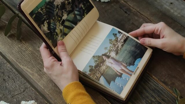 Printed memories. Female hands leaf through photo album with printed photos.