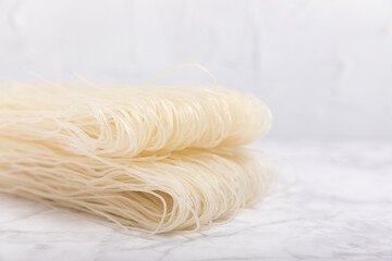 rice noodles. Noodles with rice flour on a white marble background. Funchoza. Dry rice noodles.Close-up.Copy space. Place for text.