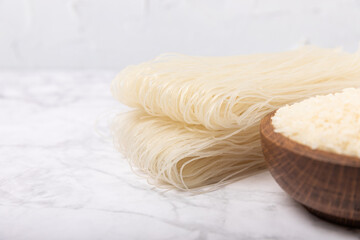 rice noodles. Noodles with rice flour on a white marble background. Funchoza. Dry rice noodles.Close-up.Copy space. Place for text.