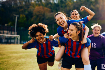 Multiracial women's soccer team having fun and celebrating after winning the match.