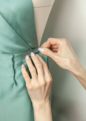 Dressmaker works with a dress on a mannequin in the atelier, close-up