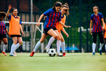 Athletic women playing soccer during sports training at stadium.