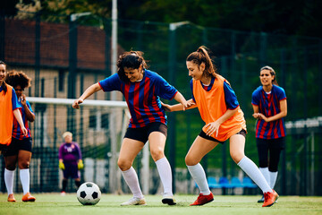 Obraz premium Female players in action during practice on soccer pitch.